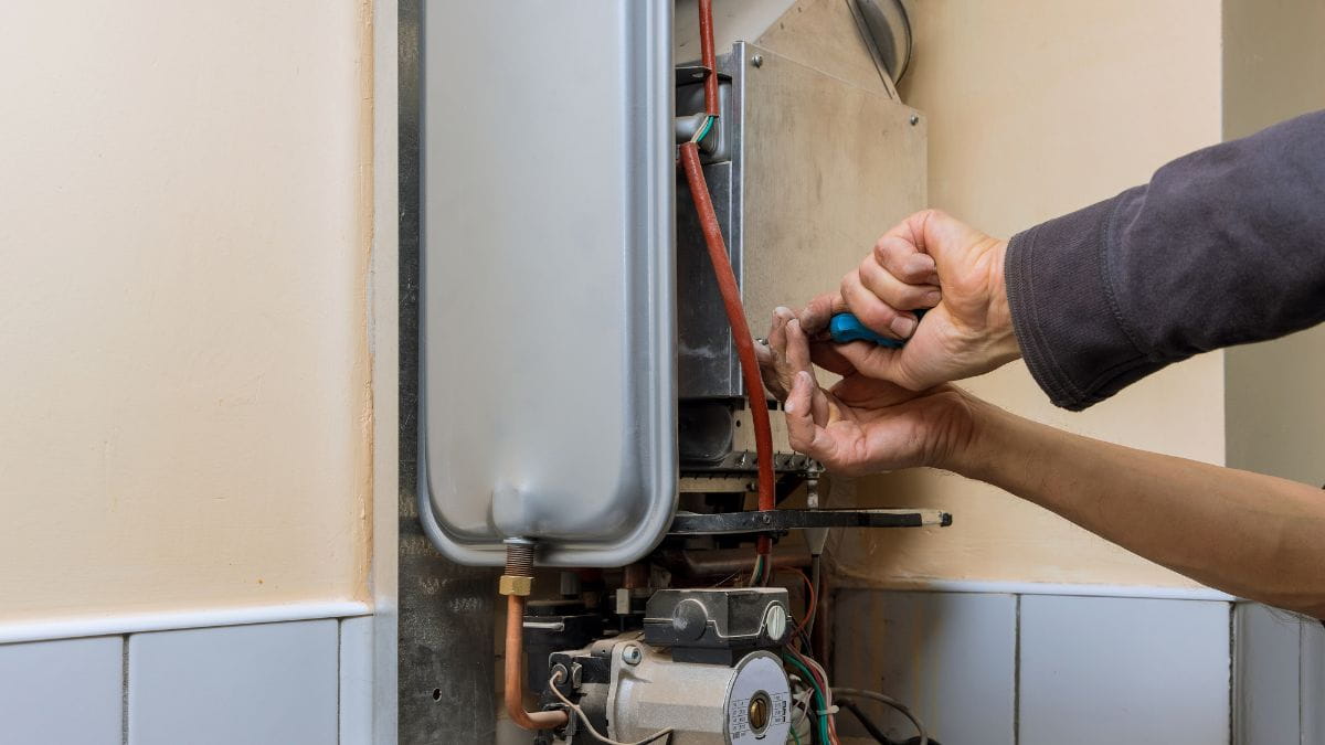 Specialist herstelt de leidingen van een gasketel met de nodige voorzorgsmaatregelen en beschermende kledij